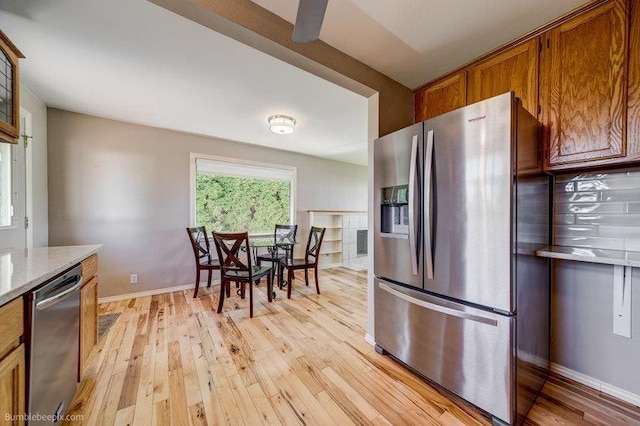 4023 W Hoffman Ave, Spokane, WA 99205 - kitchen with light wood-style flooring, baseboards, light stone counters, brown cabinets, and stainless steel appliances