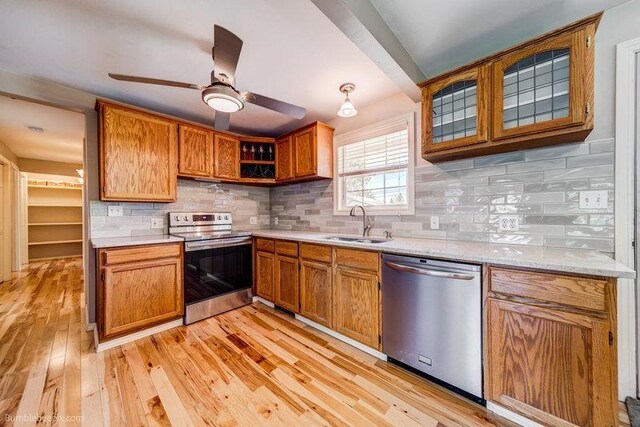 4023 W Hoffman Ave, Spokane, WA 99205 - kitchen with appliances with stainless steel finishes, a sink, decorative backsplash, brown cabinets, and light wood-type flooring