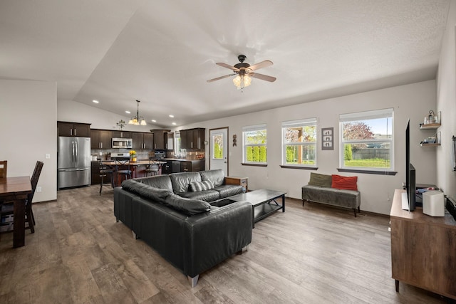 living area with lofted ceiling, ceiling fan with notable chandelier, recessed lighting, and wood finished floors