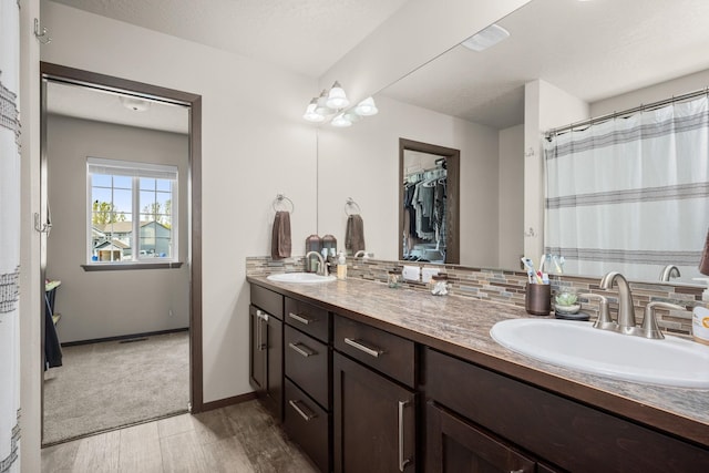full bath with double vanity, decorative backsplash, wood finished floors, and a sink