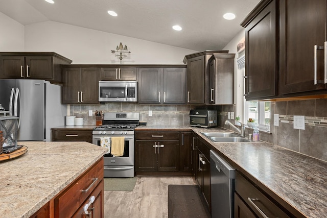 kitchen featuring light wood-style flooring, a sink, stainless steel appliances, dark brown cabinetry, and lofted ceiling