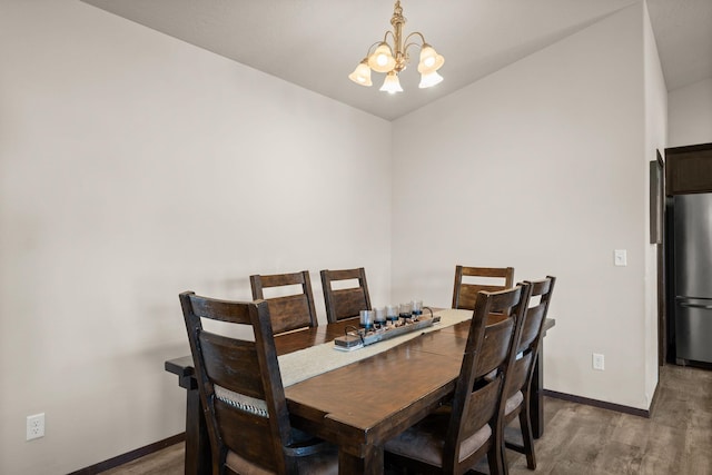 dining room with an inviting chandelier, wood finished floors, baseboards, and lofted ceiling