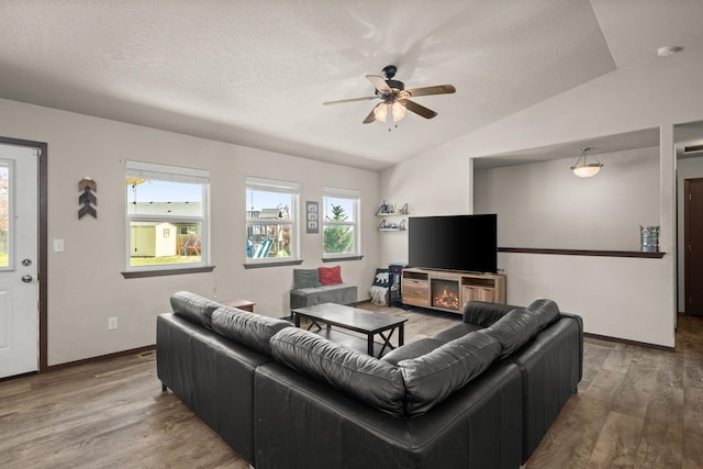 living area featuring lofted ceiling, baseboards, a ceiling fan, and wood finished floors
