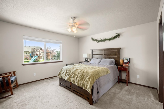 carpeted bedroom with baseboards, ceiling fan, and a textured ceiling