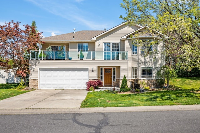 traditional-style home with a balcony, driveway, a front yard, a garage, and stone siding