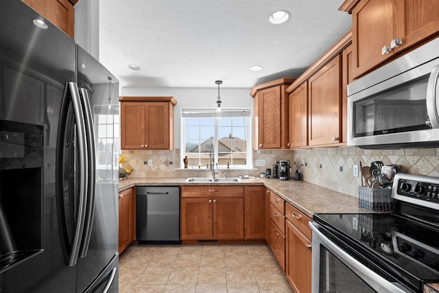 kitchen with pendant lighting, brown cabinets, decorative backsplash, and appliances with stainless steel finishes
