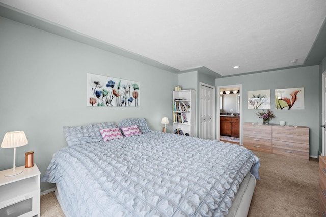 carpeted bedroom featuring ensuite bathroom and a closet