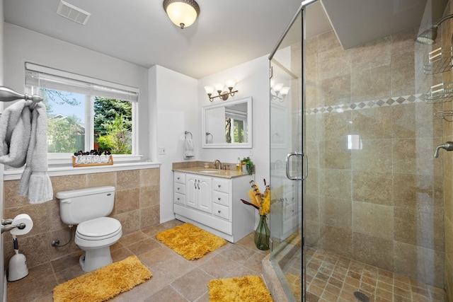full bathroom featuring toilet, tile walls, vanity, visible vents, and a shower stall