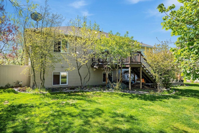 back of property featuring stairway, a wooden deck, fence, and a lawn