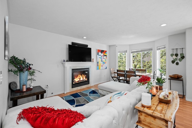 living room with recessed lighting, baseboards, a glass covered fireplace, and wood finished floors