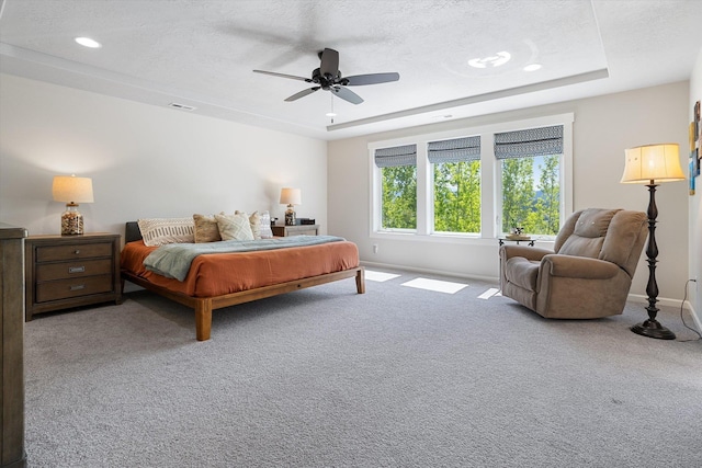 bedroom with baseboards, carpet flooring, a tray ceiling, and a ceiling fan