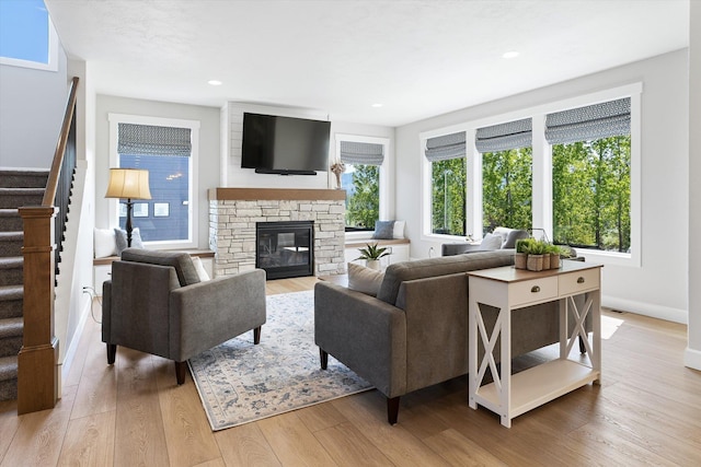 living room featuring wood finished floors, stairway, baseboards, a stone fireplace, and recessed lighting