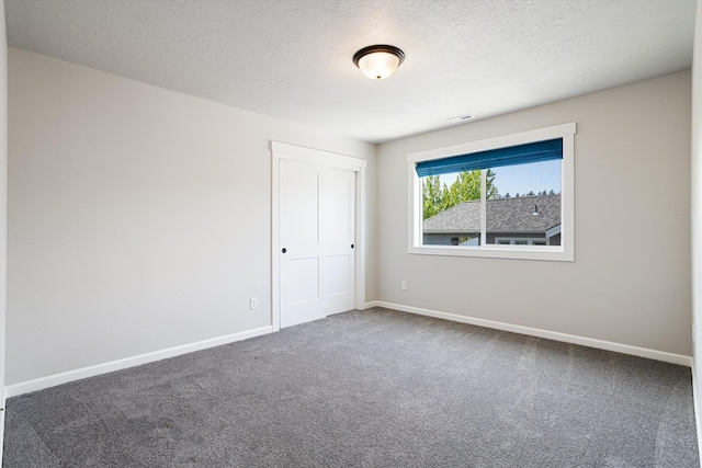 carpeted spare room with baseboards, visible vents, and a textured ceiling