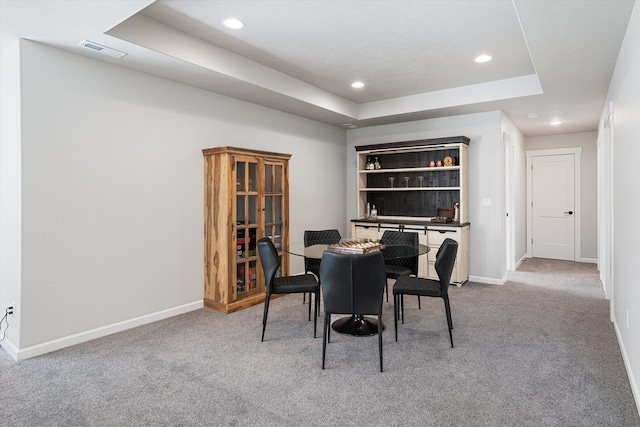 carpeted dining space featuring a tray ceiling, visible vents, baseboards, and recessed lighting