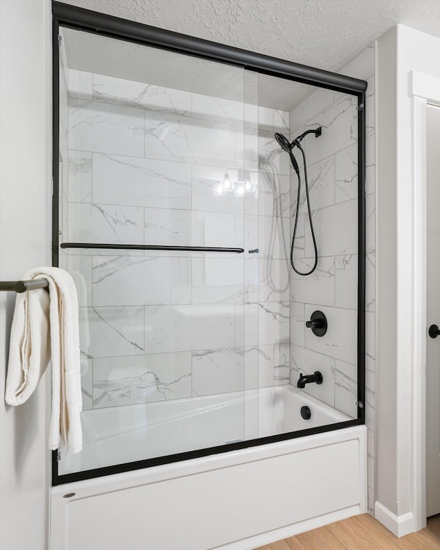 full bathroom featuring enclosed tub / shower combo, a textured ceiling, and wood finished floors