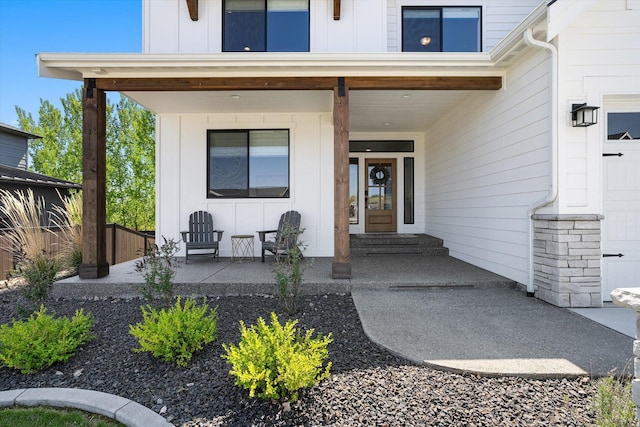 view of exterior entry with covered porch and board and batten siding