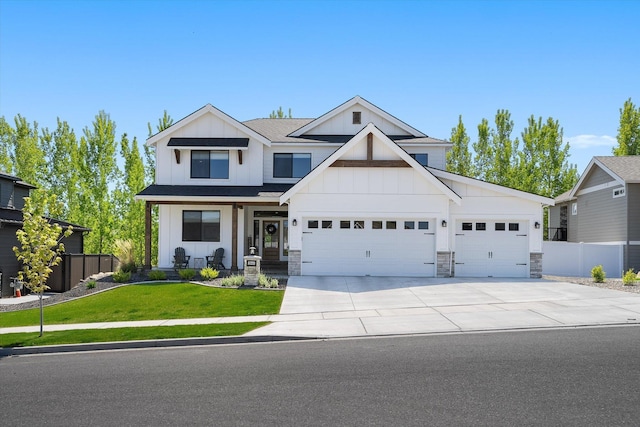 view of front of property with an attached garage, fence, board and batten siding, a front yard, and driveway