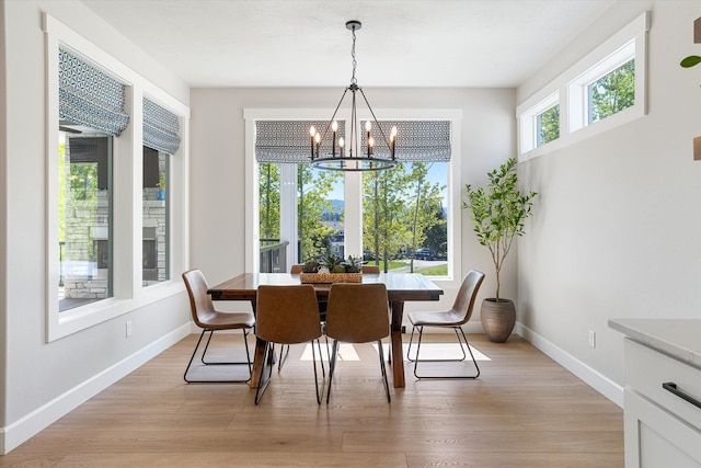 dining space featuring a chandelier, baseboards, and light wood-style floors