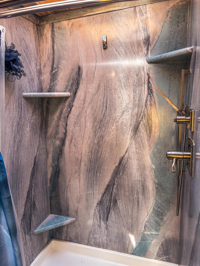 interior details featuring a marble finish shower