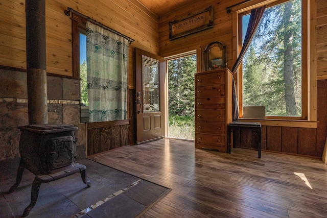 entrance foyer with a wood stove, wood walls, and wood finished floors