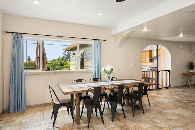dining room featuring arched walkways, baseboards, and recessed lighting