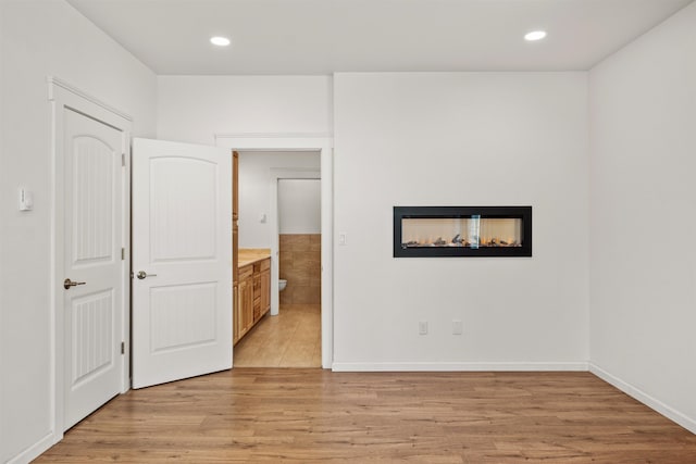 16717 E Washington Rd, Valleyford, WA 99036 - unfurnished bedroom with light wood-style floors, a multi sided fireplace, recessed lighting, and baseboards
