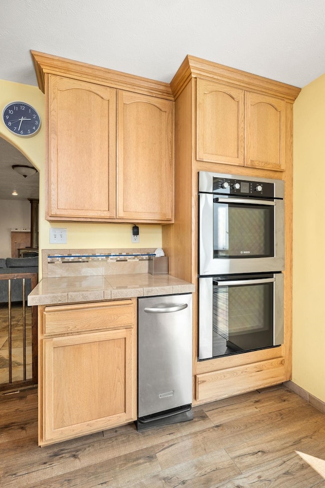 kitchen with light wood-style flooring, light brown cabinets, and double oven