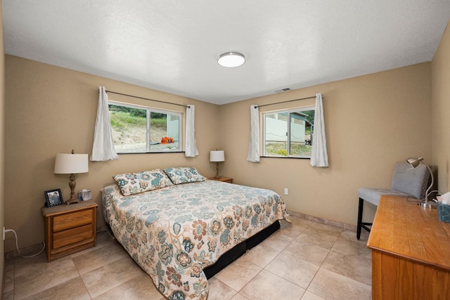 bedroom featuring light tile patterned floors, visible vents, and baseboards