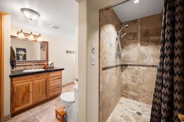 bathroom with toilet, vanity, visible vents, tile patterned floors, and a tile shower