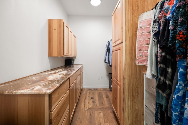 clothes washing area featuring light wood-style flooring and baseboards