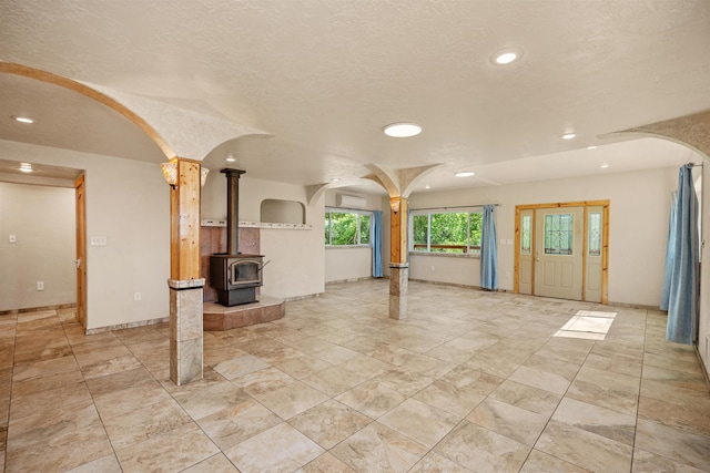 16717 E Washington Rd, Valleyford, WA 99036 - unfurnished living room featuring arched walkways, recessed lighting, a wood stove, baseboards, and decorative columns