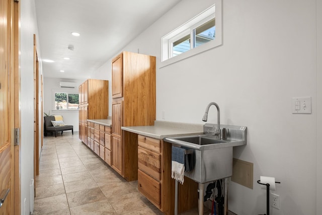 kitchen featuring light countertops, a sink, a wall mounted AC, and recessed lighting