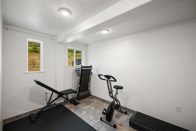 exercise area featuring baseboards and light tile patterned flooring