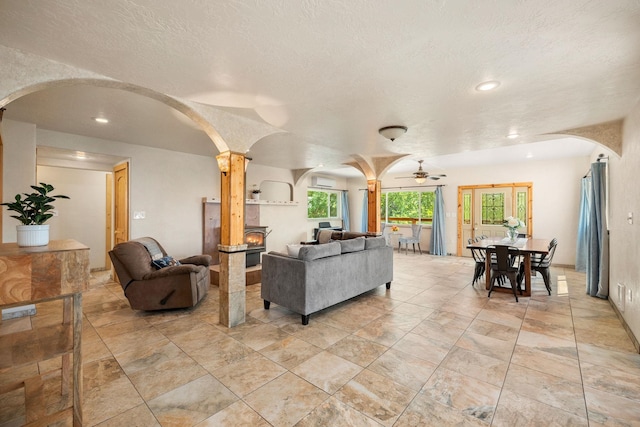 living area featuring arched walkways, a ceiling fan, ornate columns, and recessed lighting