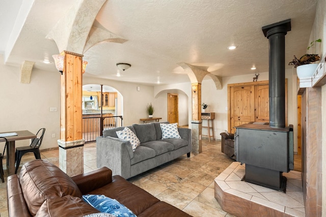 living room with light tile patterned floors, a textured ceiling, arched walkways, a wood stove, and recessed lighting