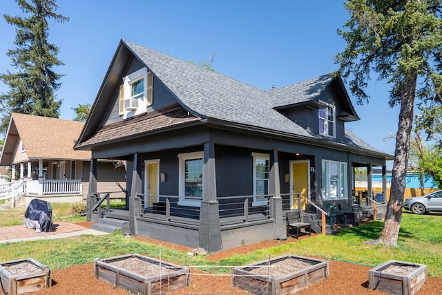 exterior space with a shingled roof, a vegetable garden, a porch, and a yard