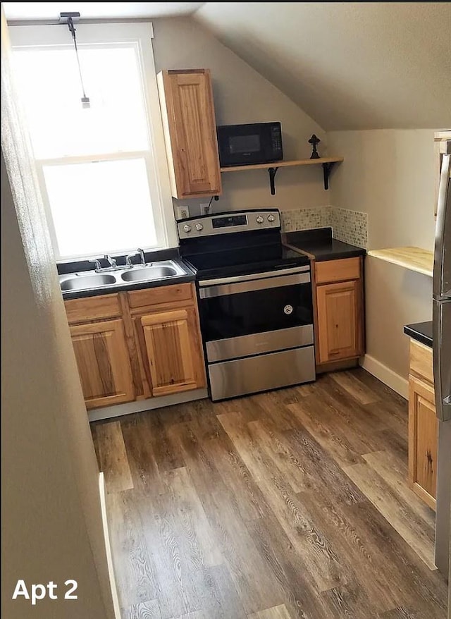 kitchen with a sink, lofted ceiling, black microwave, stainless steel electric range oven, and dark countertops