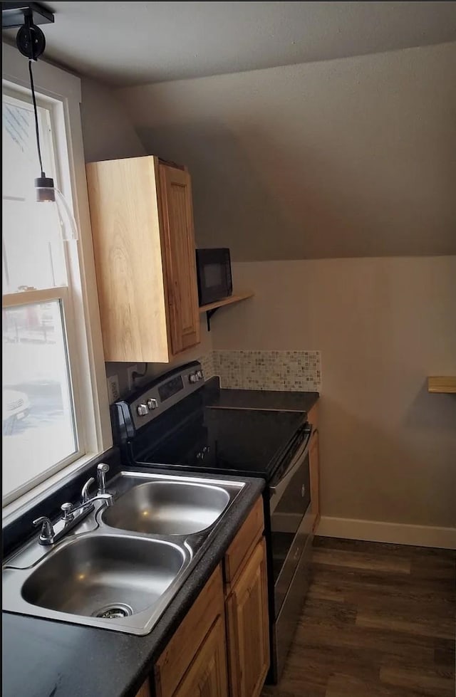kitchen with a sink, brown cabinetry, range with electric stovetop, dark wood finished floors, and dark countertops