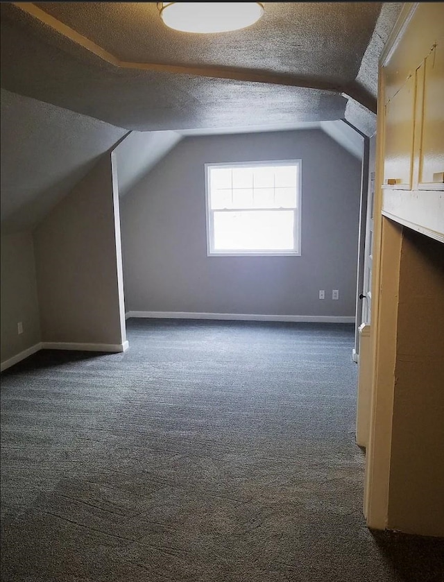 bonus room featuring baseboards, dark carpet, and vaulted ceiling