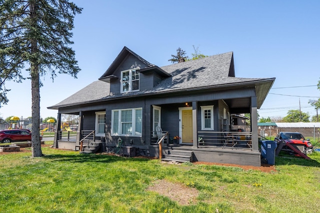 bungalow featuring a front lawn, a porch, roof with shingles, and fence