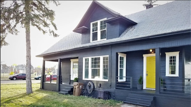 view of side of home with covered porch, a yard, and a chimney