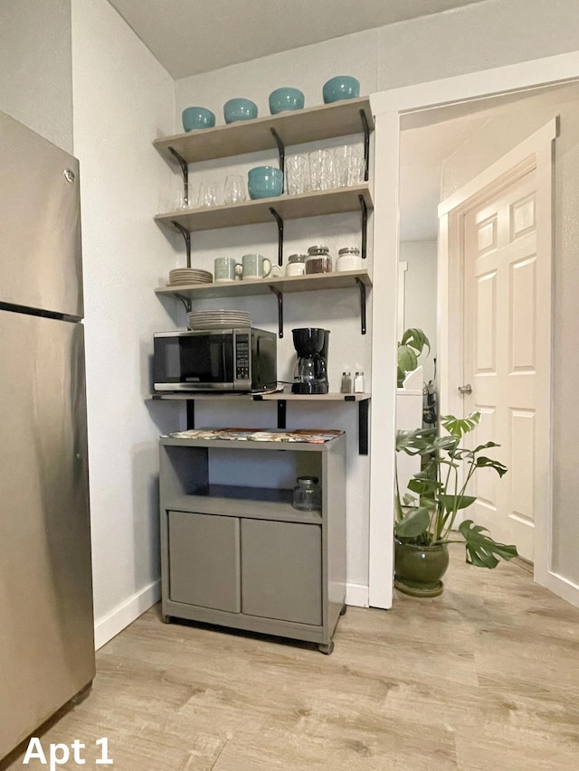 bar with appliances with stainless steel finishes, light wood-style flooring, and baseboards