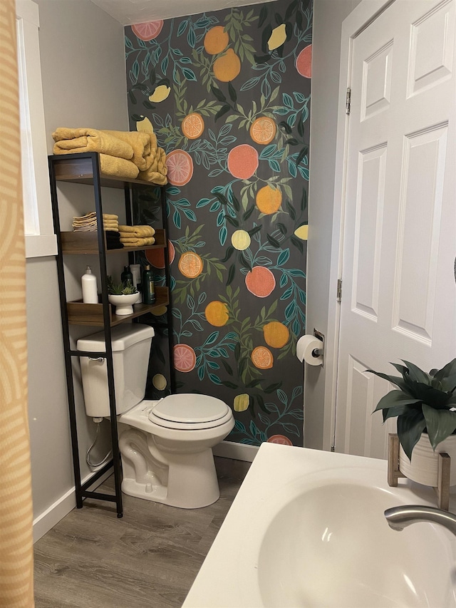 bathroom featuring toilet, baseboards, a sink, and wood finished floors