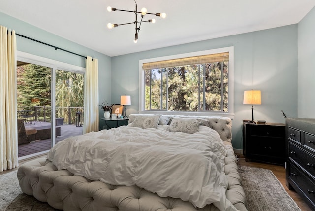 bedroom with dark wood-style flooring, a notable chandelier, multiple windows, and access to exterior