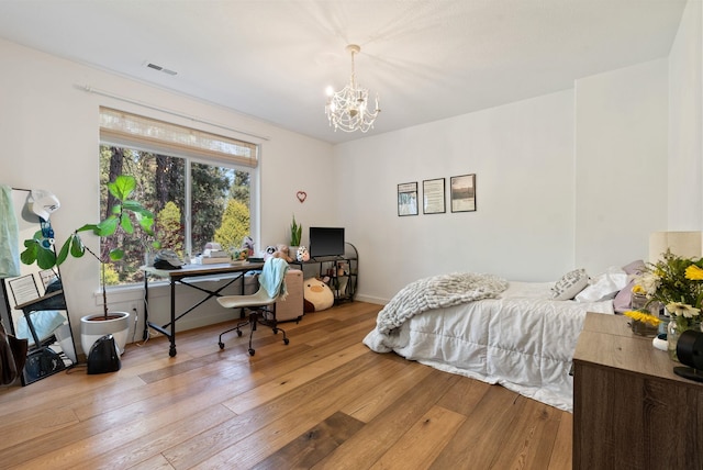 bedroom with an inviting chandelier, visible vents, baseboards, and hardwood / wood-style flooring