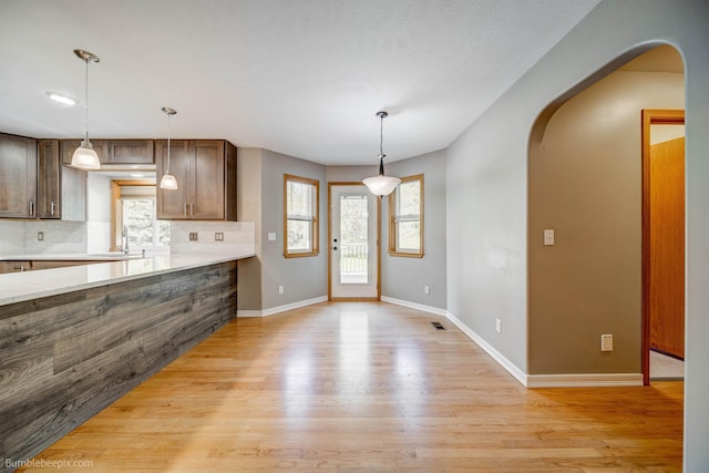 2712 W Eden Ln, Deer Park, WA 99006 - kitchen featuring light wood-type flooring, a healthy amount of sunlight, decorative backsplash, arched walkways, and light countertops