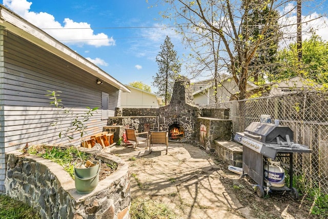 view of patio with grilling area, fence, and an outdoor stone fireplace