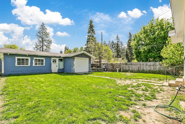 back of property with a lawn, an attached garage, and a fenced backyard