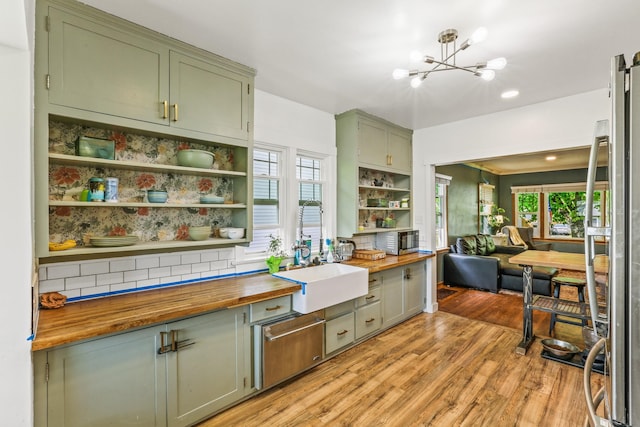 kitchen with a sink, butcher block countertops, open shelves, light wood-style flooring, and green cabinets