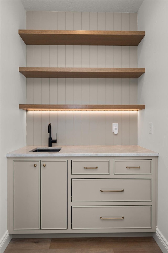 bar featuring a sink, baseboards, and wood finished floors